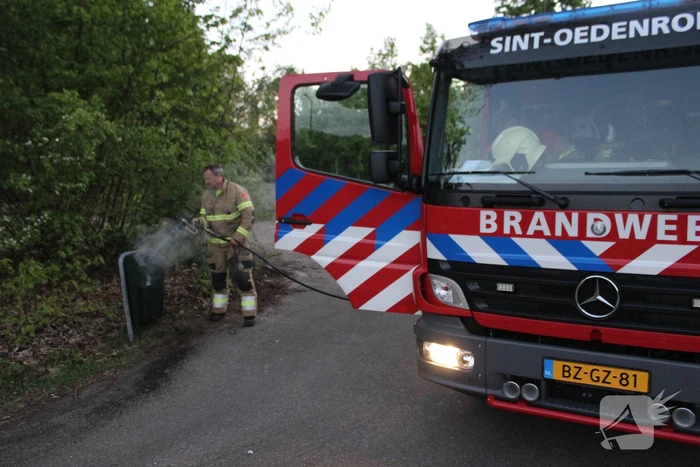 Omstanders doven vuur in prullenbak op parkeerterrein