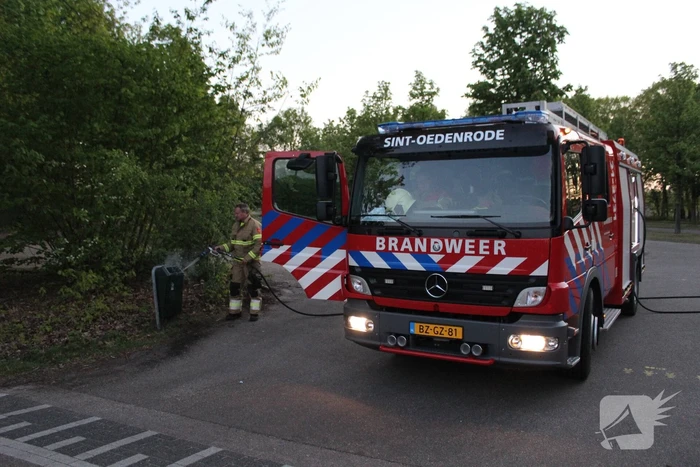Omstanders doven vuur in prullenbak op parkeerterrein