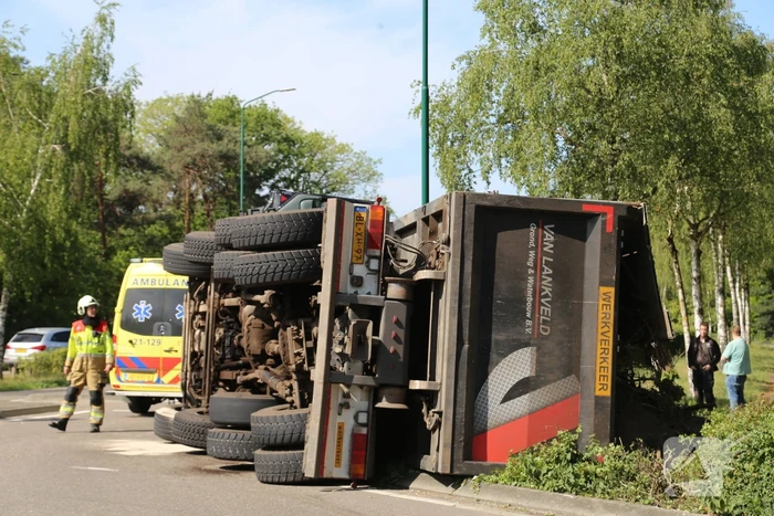 Vrachtwagen met tuinafval gekanteld op rotonde