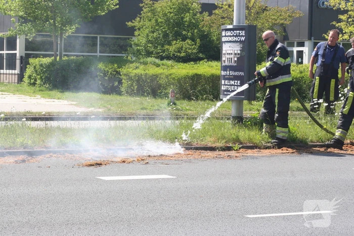 Brandweer blust brandend gras in berm