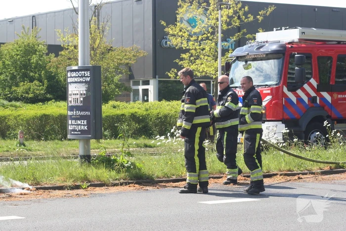 Brandweer blust brandend gras in berm