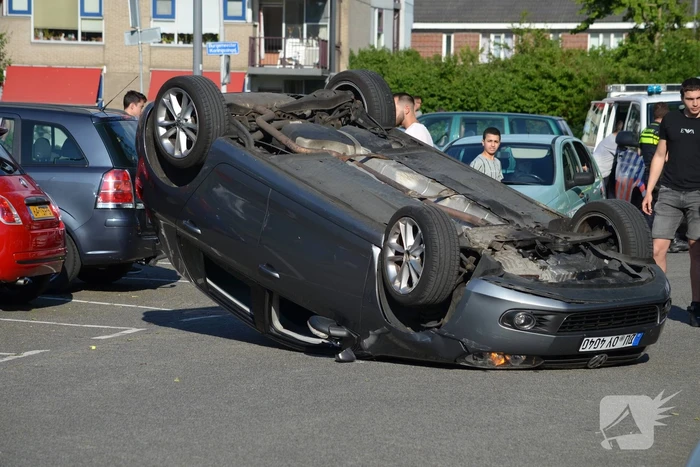 Auto op zijn kop na aanrijding met geparkeerde auto