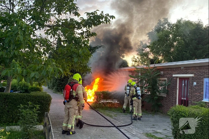 Auto verwoest door brand voor gevel woonhuis
