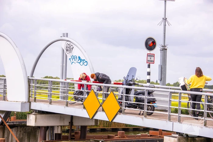 Fietsers kruipen onder slagbomen Malebrug