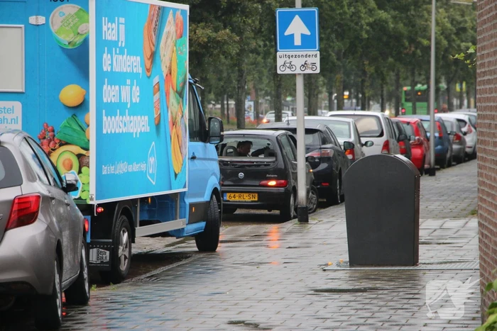 Boodschappenbus klapt achterop auto voor rotonde