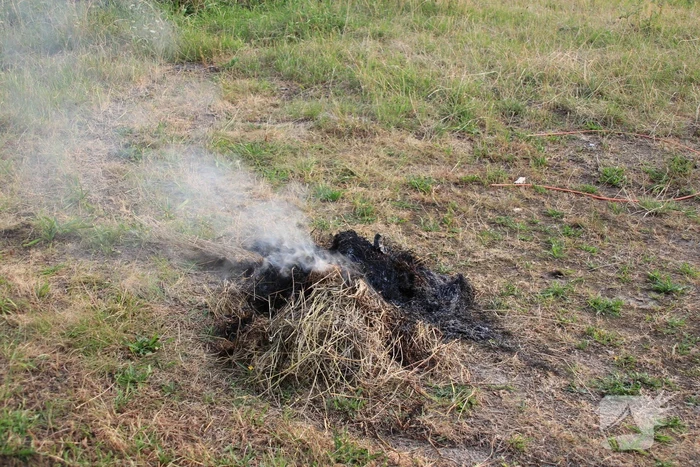Buurtbewoner blust een hoop in brand gevlogen hooi