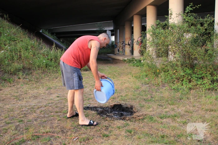 Buurtbewoner blust een hoop in brand gevlogen hooi