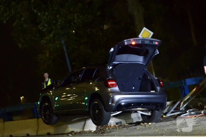 Auto belandt bovenop betonnen afscheiding