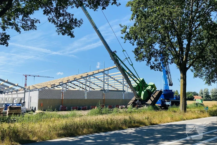 Bouwkraan achter stal omgevallen
