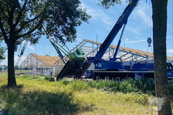 Bouwkraan achter stal omgevallen