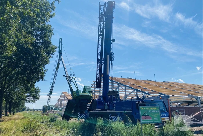 Bouwkraan achter stal omgevallen