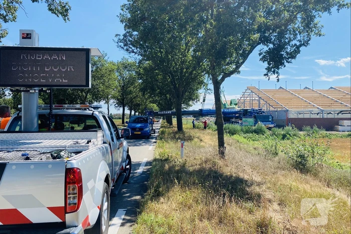 Bouwkraan achter stal omgevallen