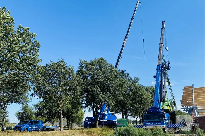 Bouwkraan achter stal omgevallen