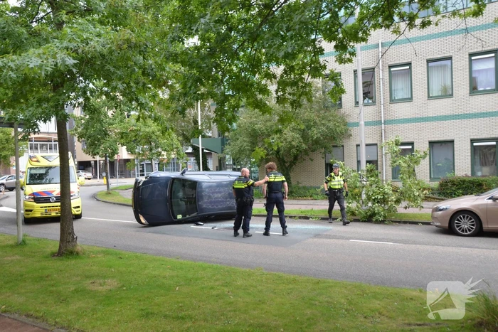 Auto vliegt uit de bocht en belandt op zijn kant