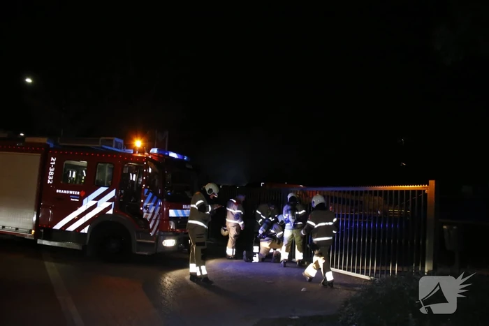 Grote berg afvalhout in brand naast houtopslag
