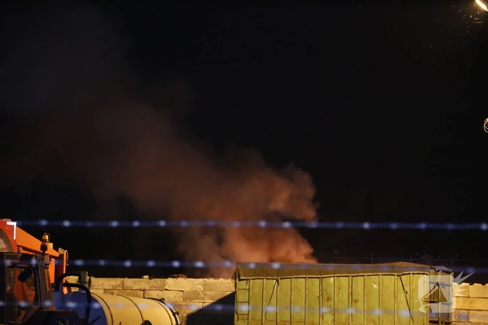 Grote berg afvalhout in brand naast houtopslag