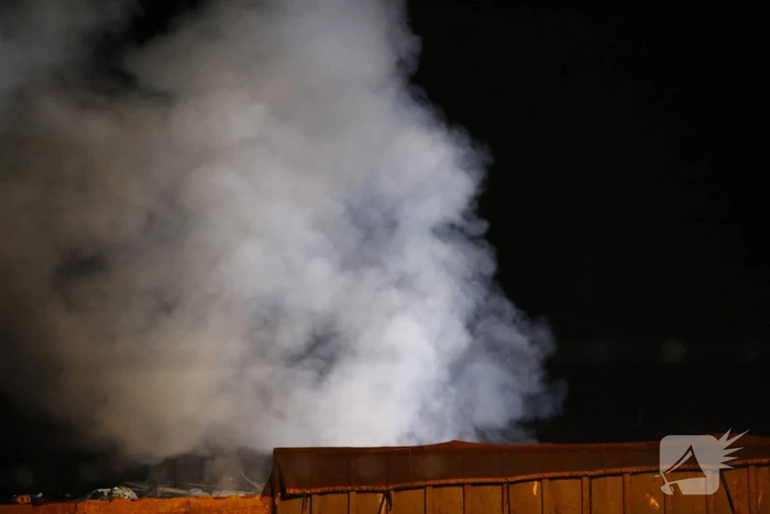 Grote berg afvalhout in brand naast houtopslag