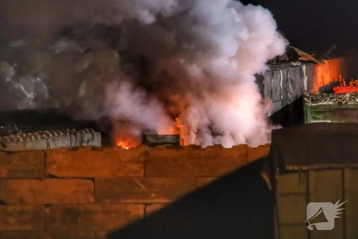 Grote berg afvalhout in brand naast houtopslag