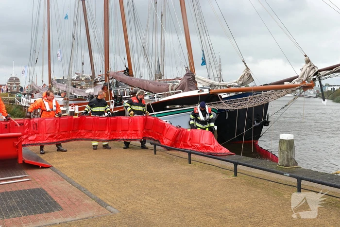 Brandweer plaats olieschermen voor lekkend zeilschip
