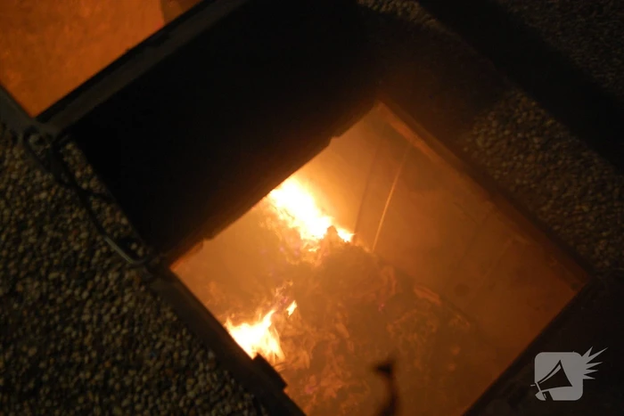 Brandweer blust brandende papiercontainer