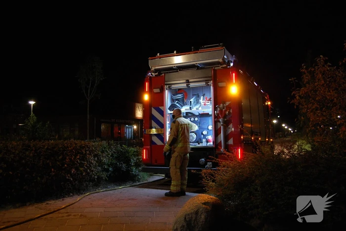 Brandweer blust brandende papiercontainer