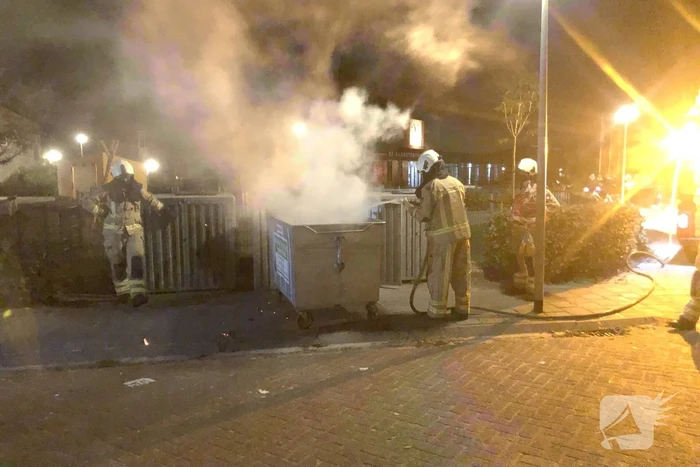 Brandweer blust brandende papiercontainer