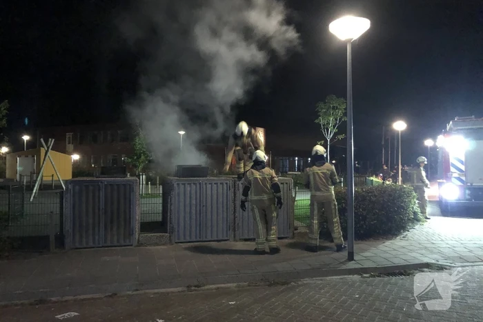 Brandweer blust brandende papiercontainer