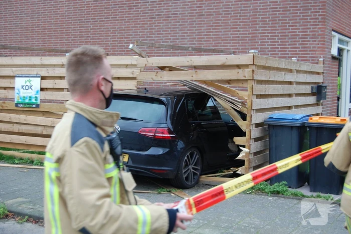Personenauto rijdt door schutting