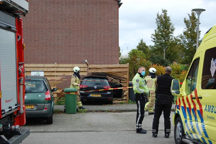 Personenauto rijdt door schutting