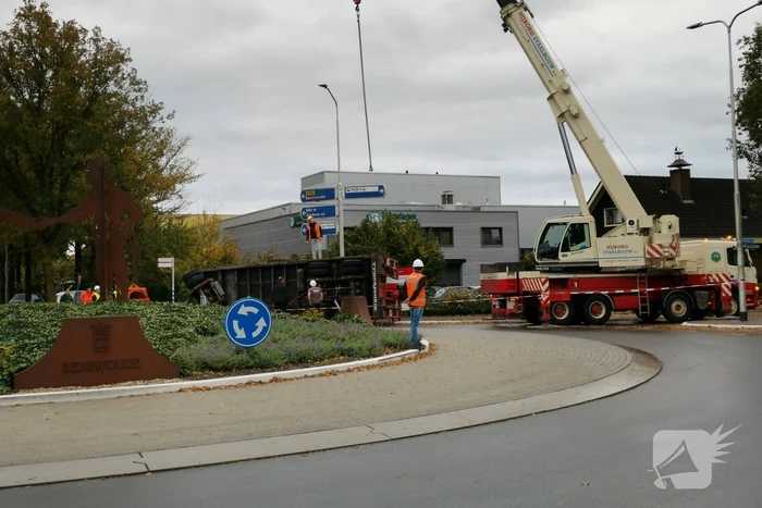 Grote aanhanger met verreiker op z'n kant op rotonde