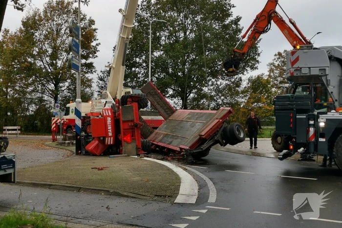 Grote aanhanger met verreiker op z'n kant op rotonde