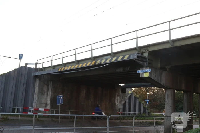 Vrachtwagen met graafmachine ramt spoorbrug