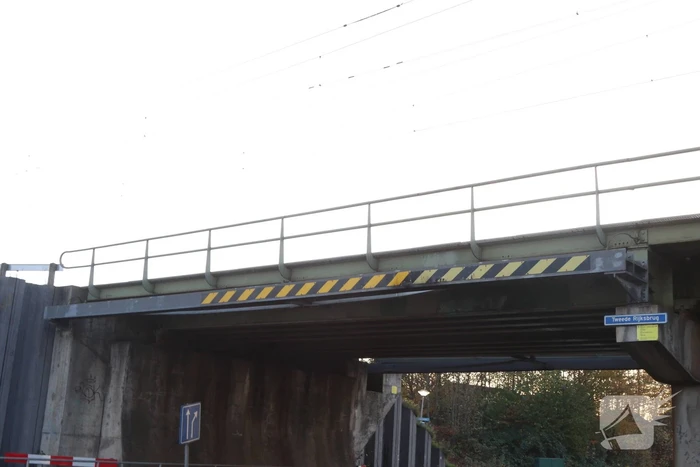 Vrachtwagen met graafmachine ramt spoorbrug