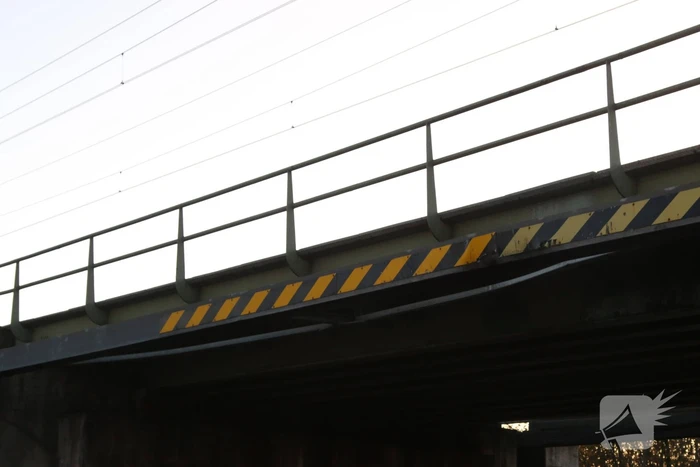 Vrachtwagen met graafmachine ramt spoorbrug