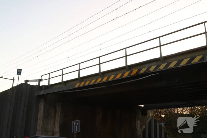 Vrachtwagen met graafmachine ramt spoorbrug