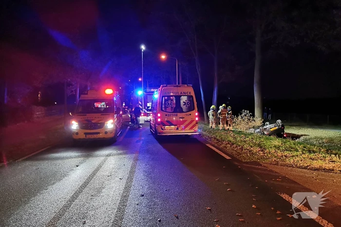 Personenauto ligt op zijn kop in berm