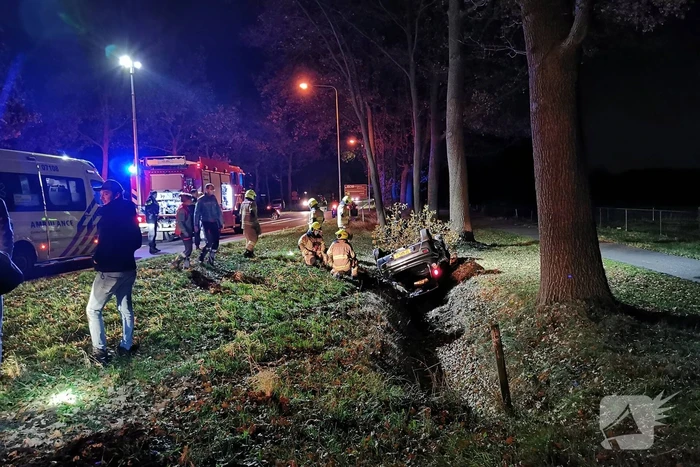 Personenauto ligt op zijn kop in berm