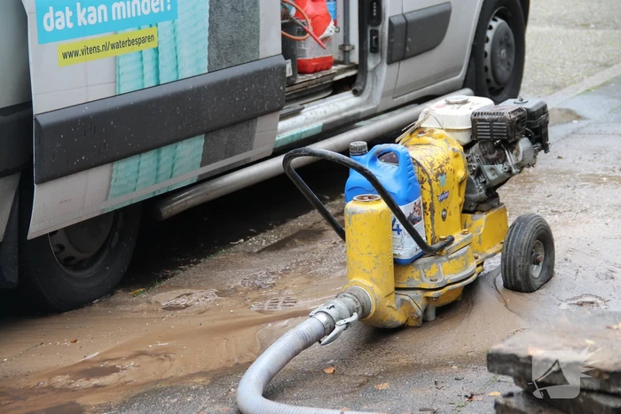Straat opengebroken door gesprongen waterleiding in Smitsveen
