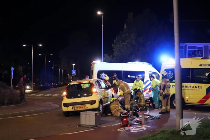Fietser bekneld onder auto