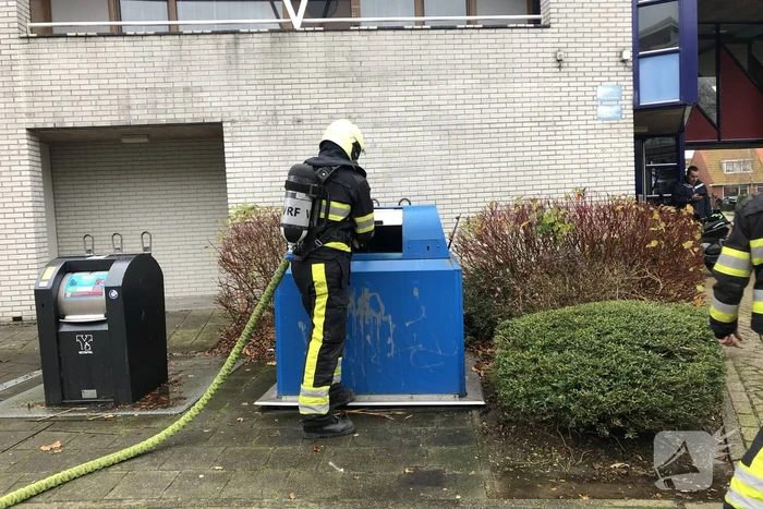 Omstanders blussen brand in papiercontainer