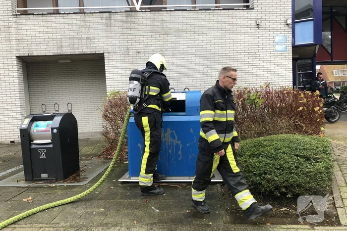 Omstanders blussen brand in papiercontainer