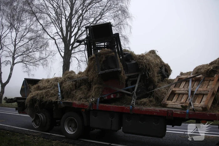 Vrachtwagen met aanhanger met hooi ramt boom