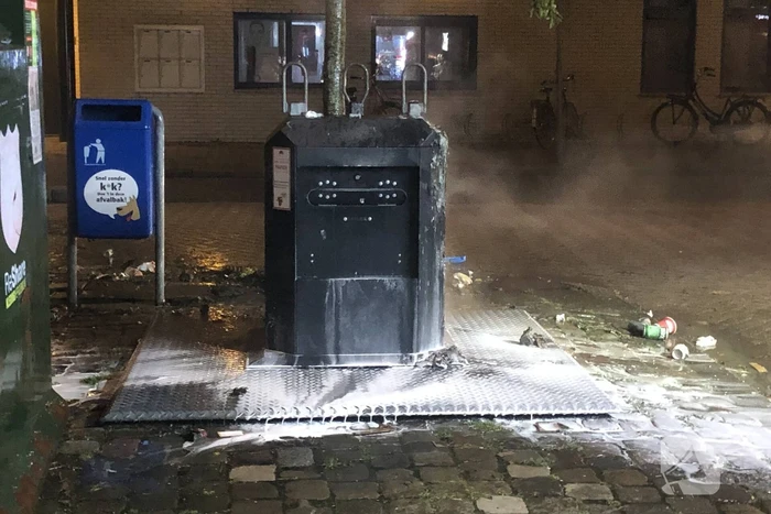 Papier in brand naast container