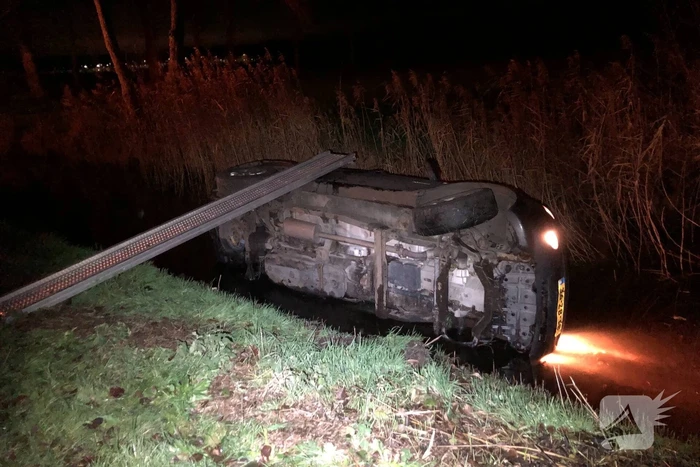 Auto vliegt uit de bocht en belandt op zijn kant in sloot