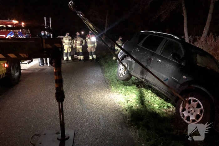 Auto vliegt uit de bocht en belandt op zijn kant in sloot