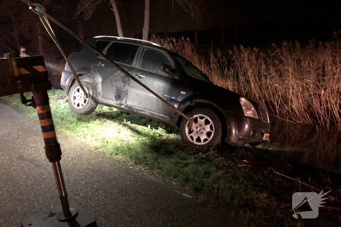 Auto vliegt uit de bocht en belandt op zijn kant in sloot