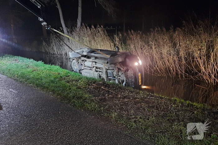 Auto vliegt uit de bocht en belandt op zijn kant in sloot