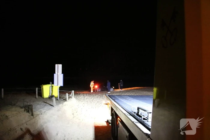 Automobilist rijdt auto vast op strand