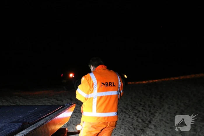 Automobilist rijdt auto vast op strand