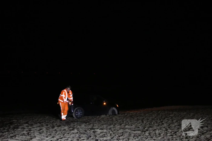Automobilist rijdt auto vast op strand